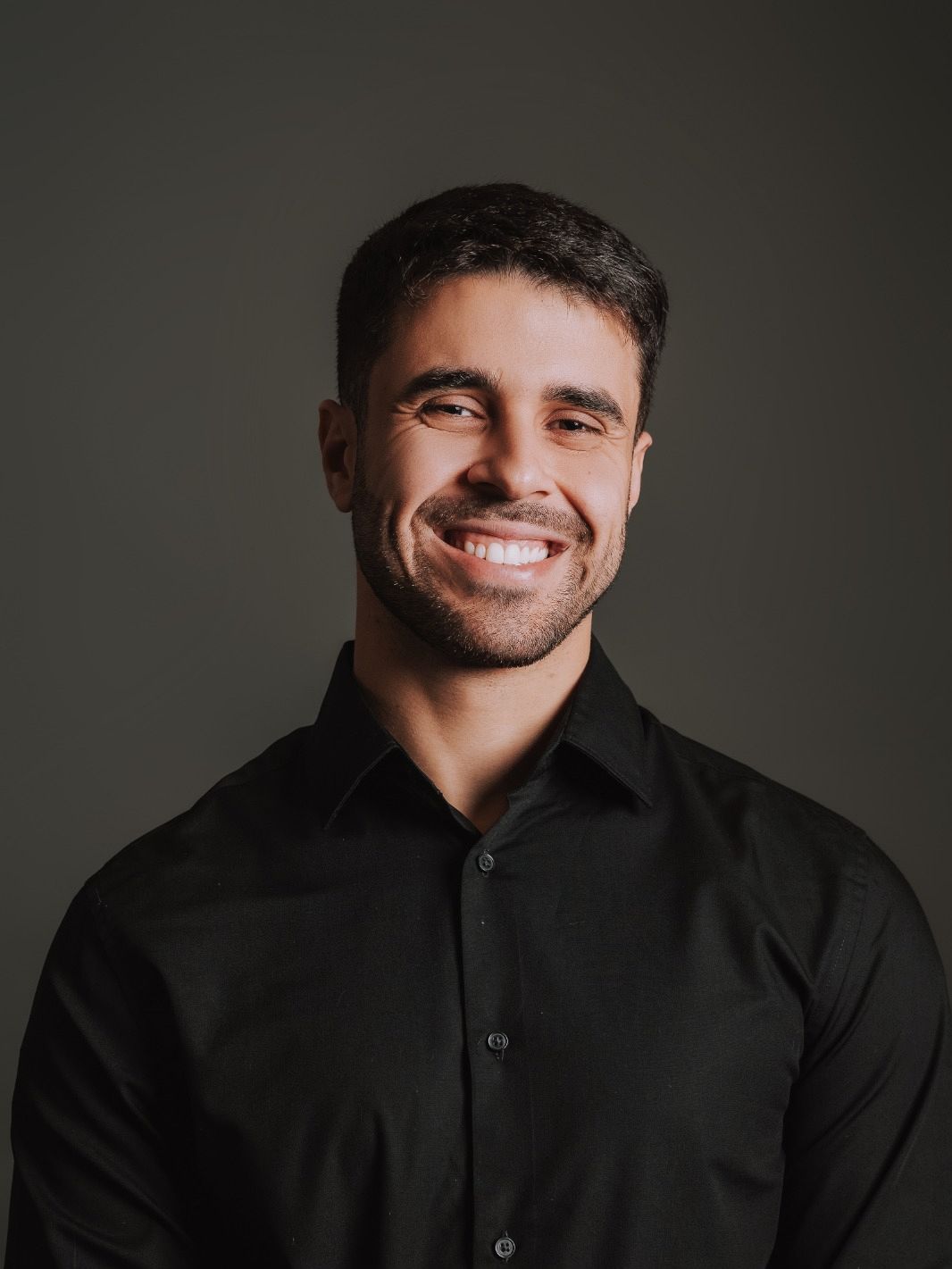 Leonardo Ferreira Santos, psicólogo, em retrato de perto, sorrindo, de camisa preta